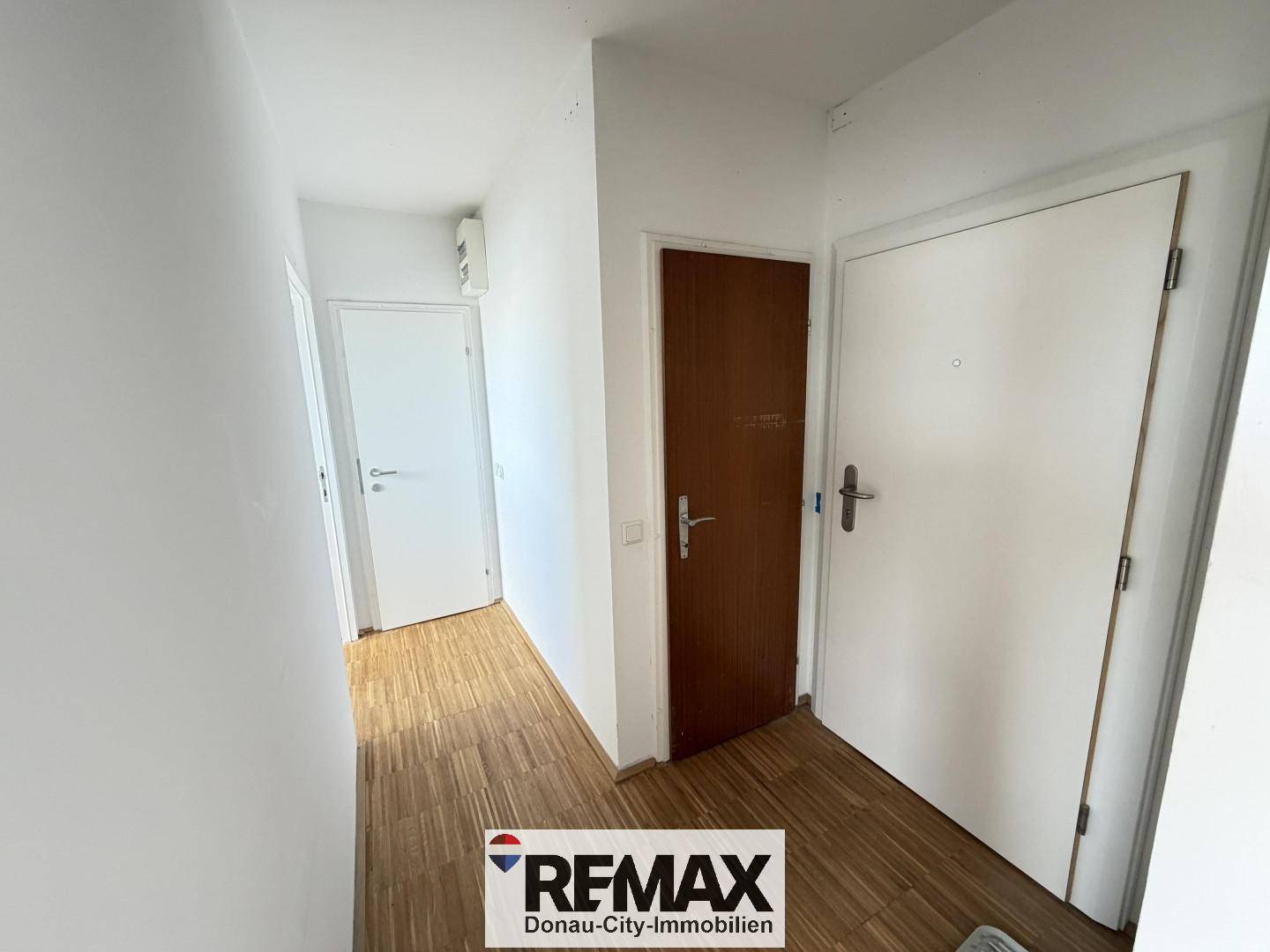 Heller Flur mit Holzboden und mehreren Türen, der zu verschiedenen Räumen führt.
