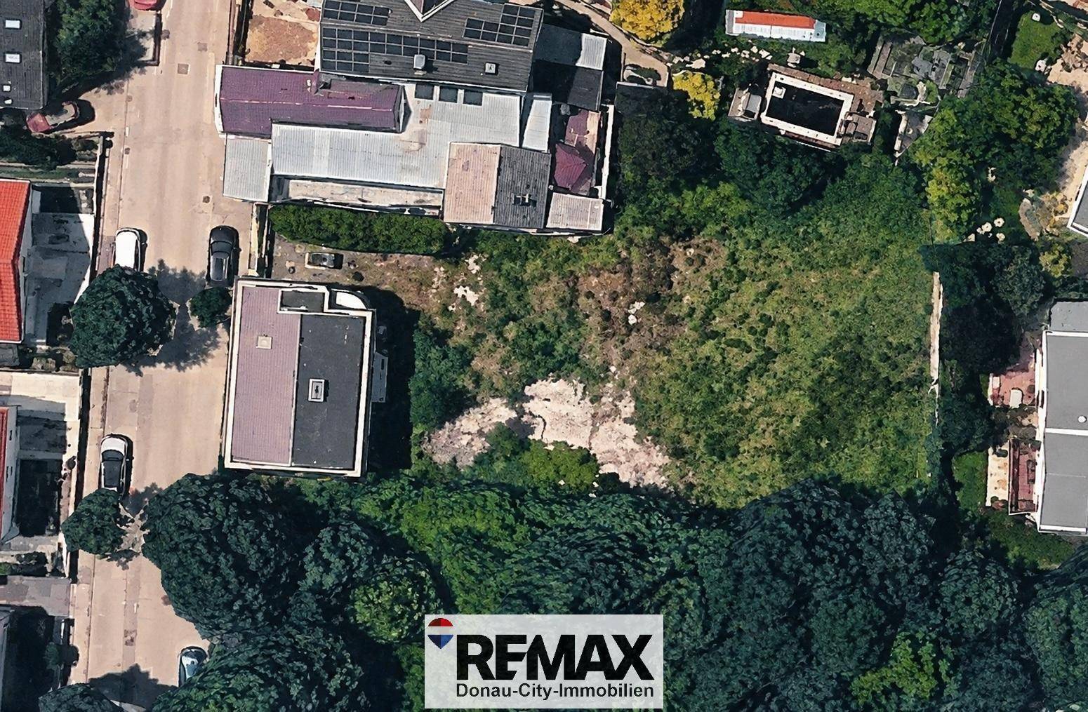 Luftaufnahme eines unbebauten Grundstücks, umgeben von Wohngebäuden und viel Grün.