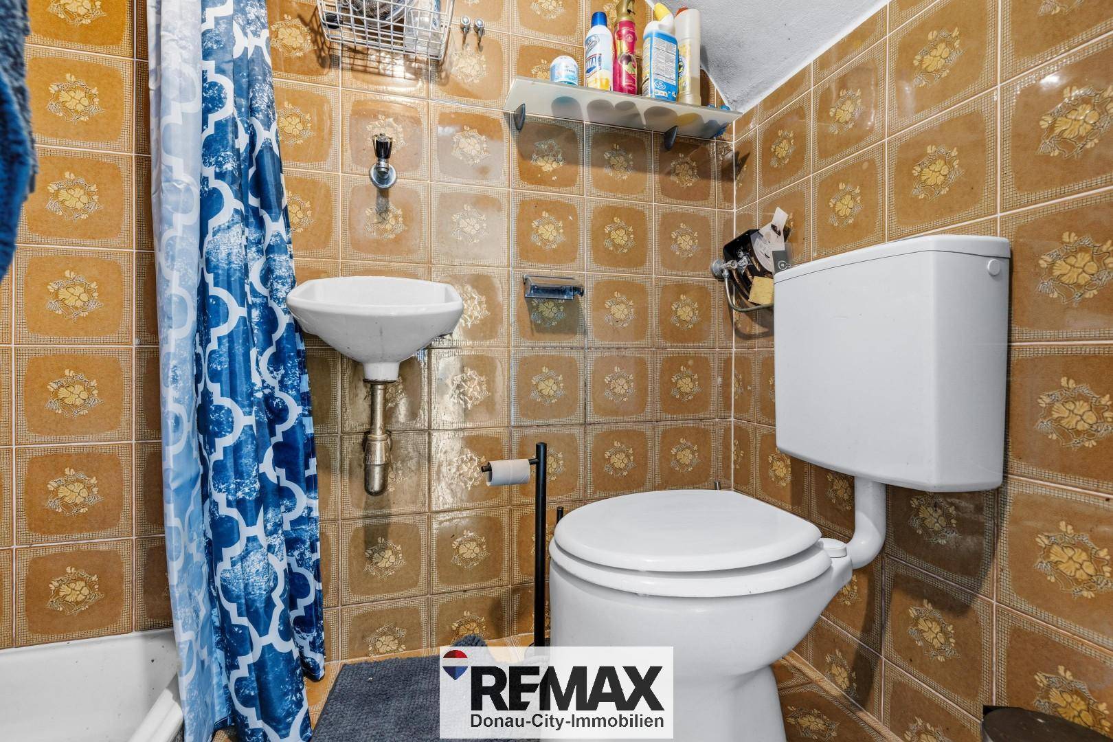 Kleines WC mit braunen Fliesen im Retro-Stil und einfacher Ausstattung.
