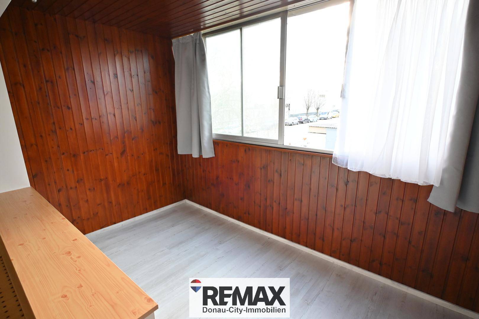 Gemütlicher Raum mit Holzvertäfelung an Wänden und Decke sowie großen Fenstern.