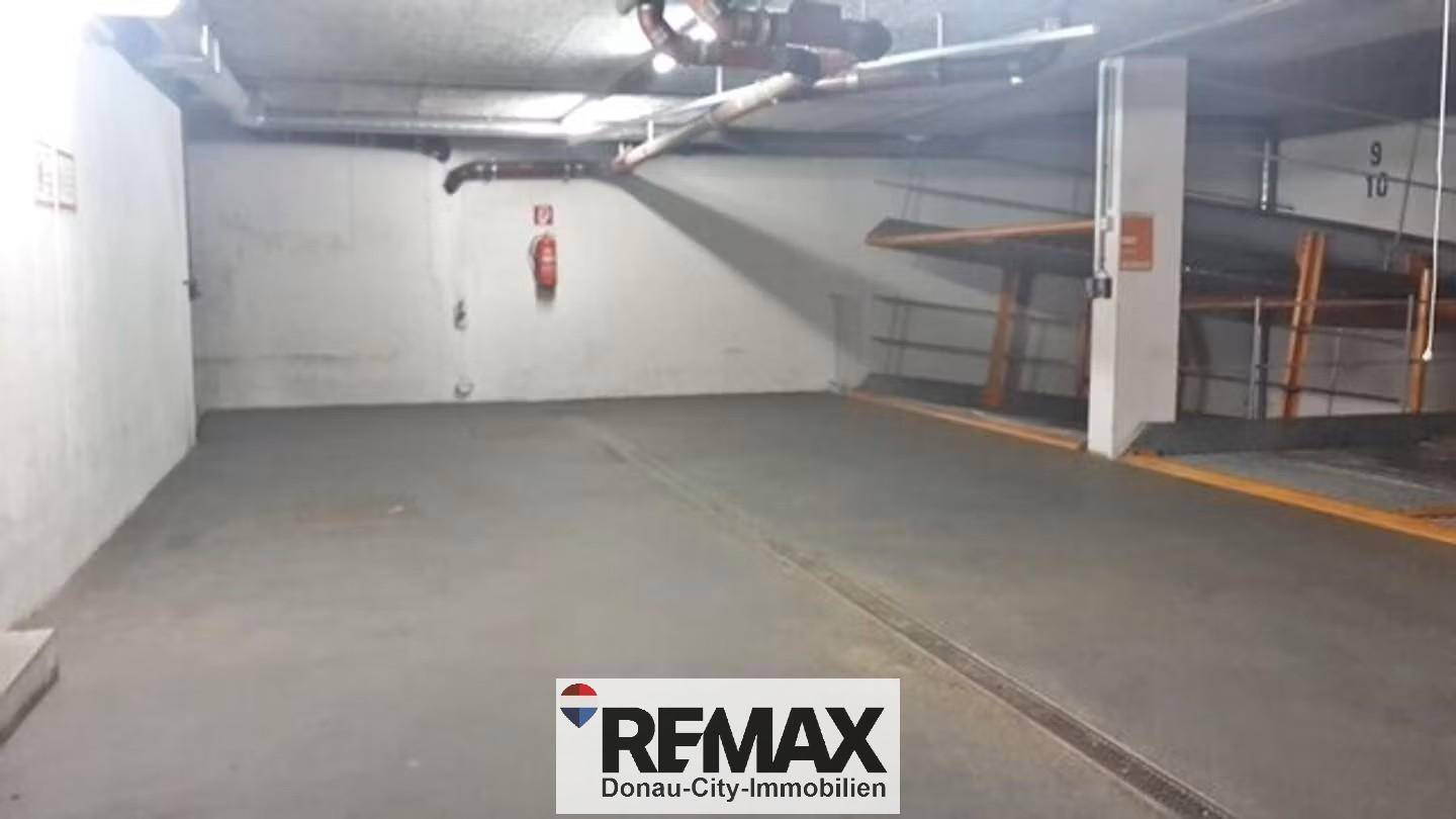 Ein weiterer Bereich der Tiefgarage mit Betonboden und sichtbaren Installationen an der Decke.