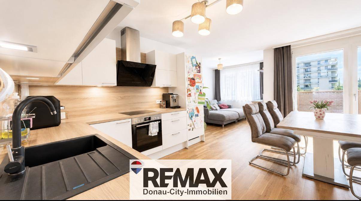 Offener Wohn- und Essbereich mit moderner Küche und Zugang zum Balkon.