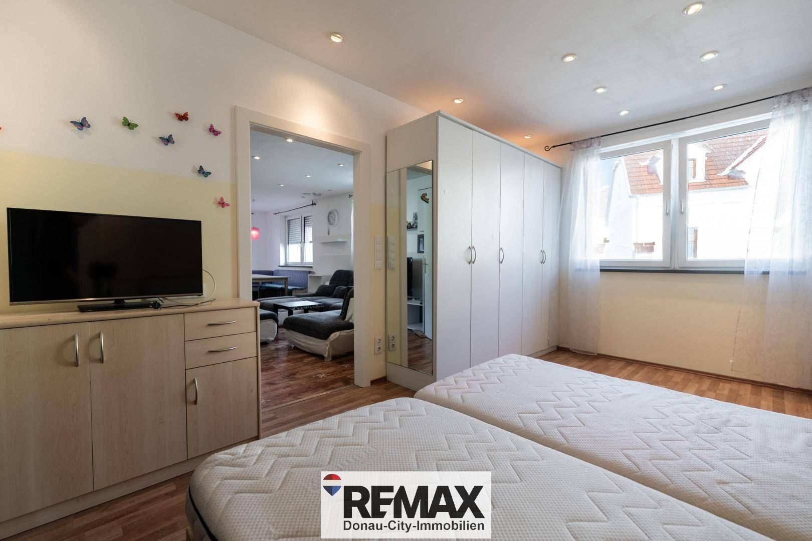 Schlafzimmer mit zwei Betten, Fernseher und großem Kleiderschrank mit Spiegel.