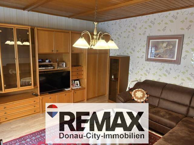 Gemütliches Wohnzimmer mit Holzdecke, traditionellen Möbeln und braunem Sofa.