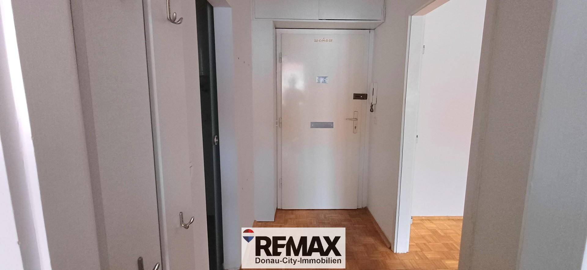 Eingangsbereich mit Garderobe und einer weißen Eingangstür, die in die Wohnung führt.