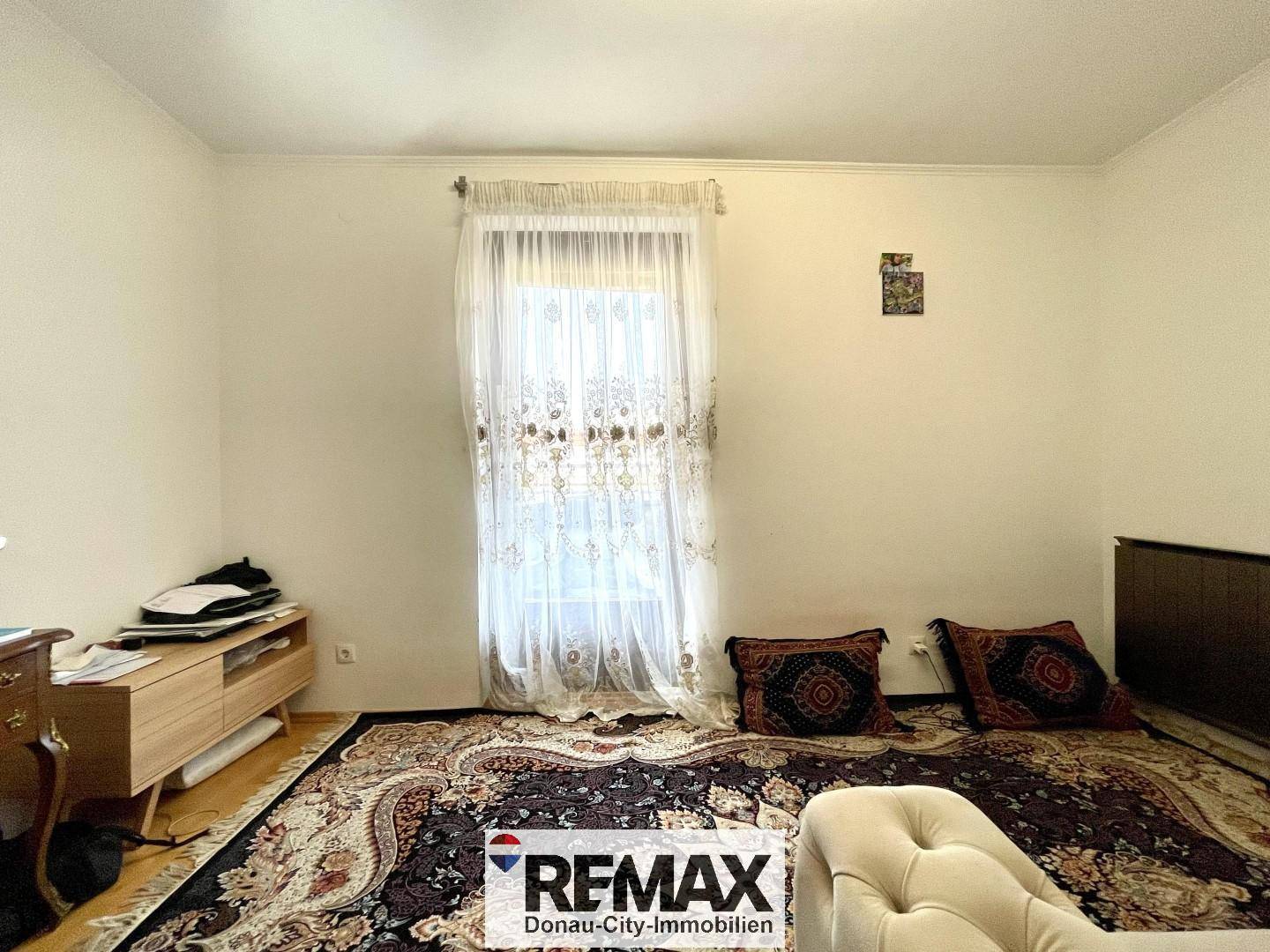 Helles Zimmer mit Fenster, niedrigem Schrank und gemustertem Teppich, vielseitig nutzbar.