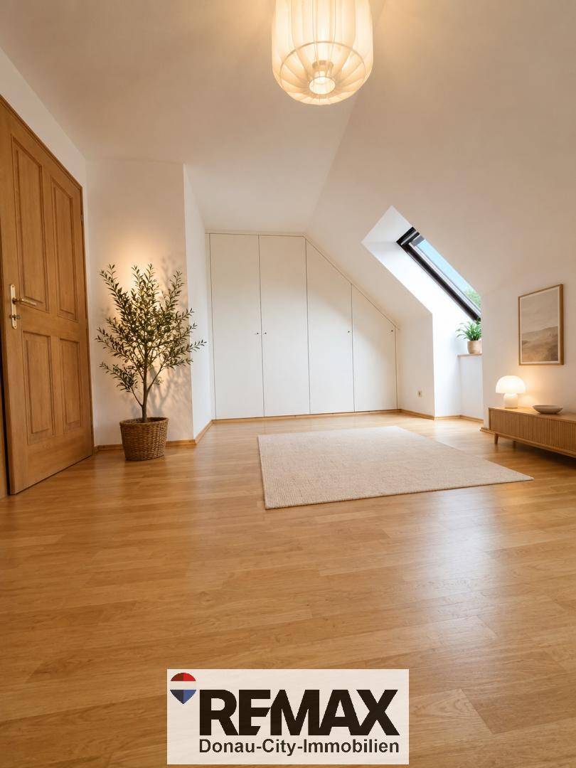 Geräumiges Schlafzimmer mit Holzboden, Einbauschränken und Dachfenster.