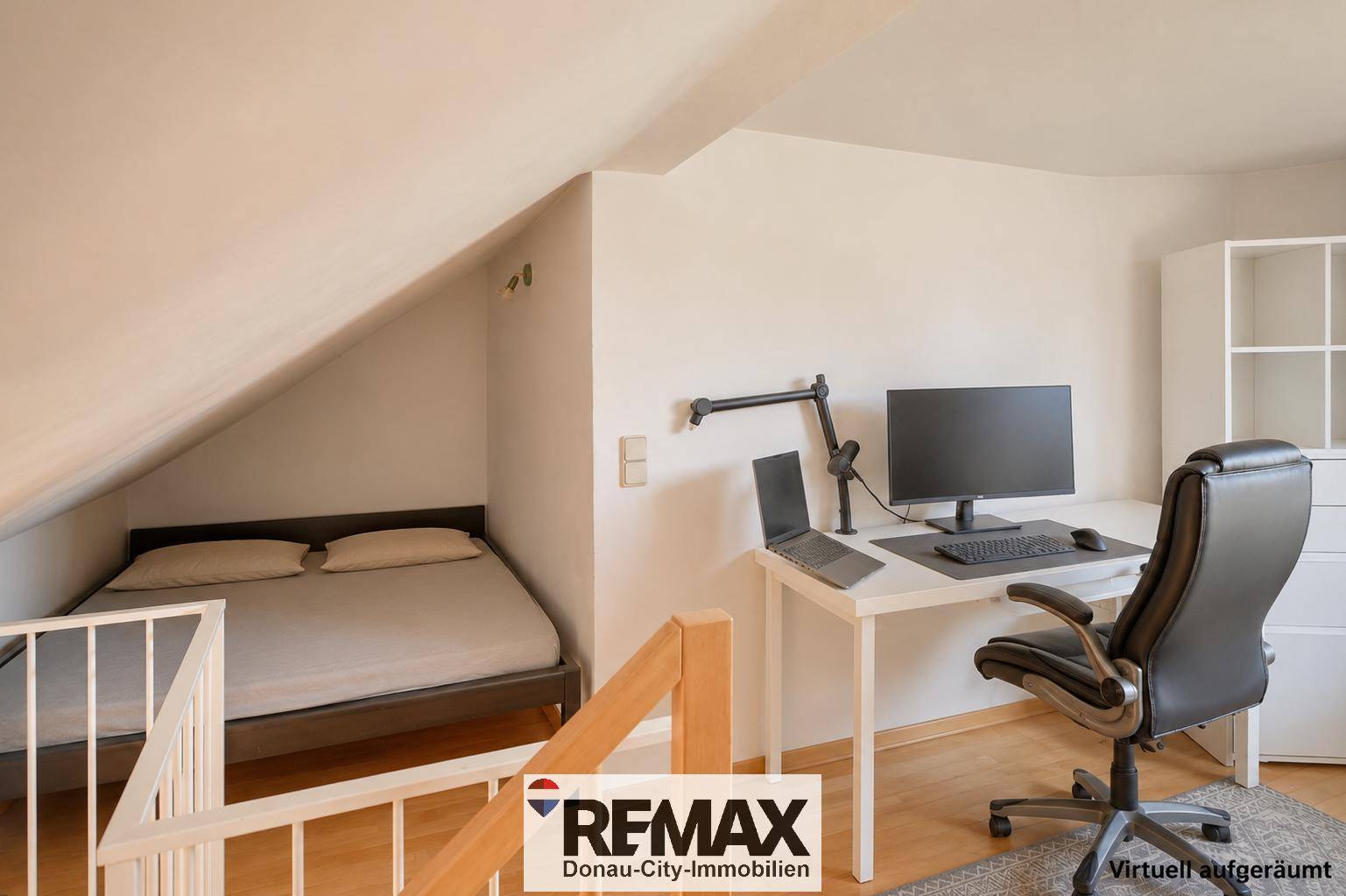 Schlaf- und Arbeitsbereich unter einer Dachschräge mit Bett, Schreibtisch und Computer.