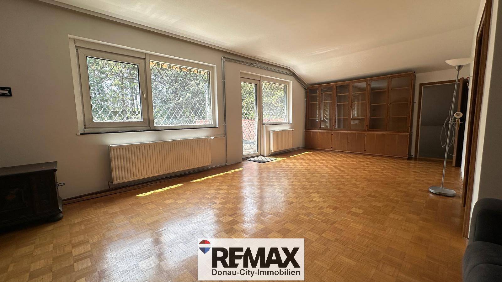 Großzügiges Wohnzimmer mit Parkettboden, Einbauschrank und Zugang zum Balkon.