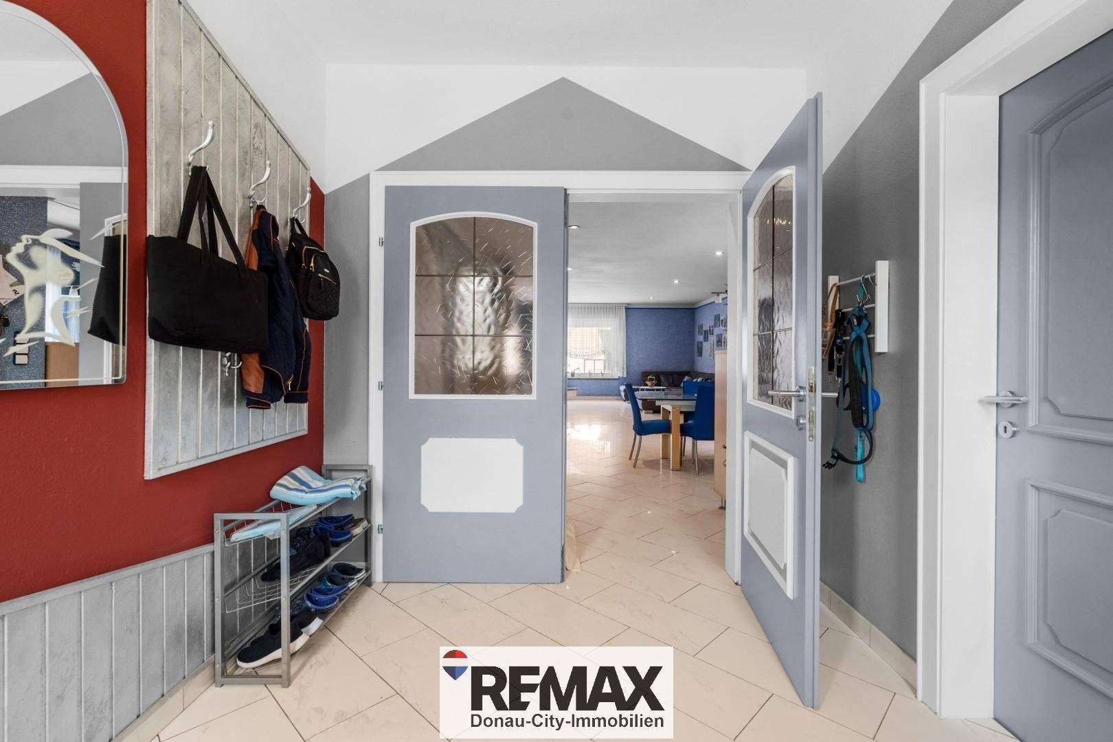 Freundlicher Eingangsbereich mit Fliesenboden, Garderobe und Blick in den offenen Wohnbereich.