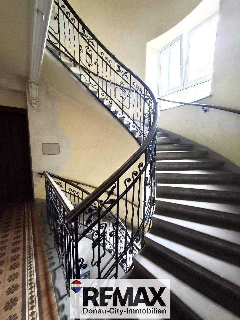 Elegantes Treppenhaus mit schmiedeeisernem Geländer und natürlichem Lichteinfall.