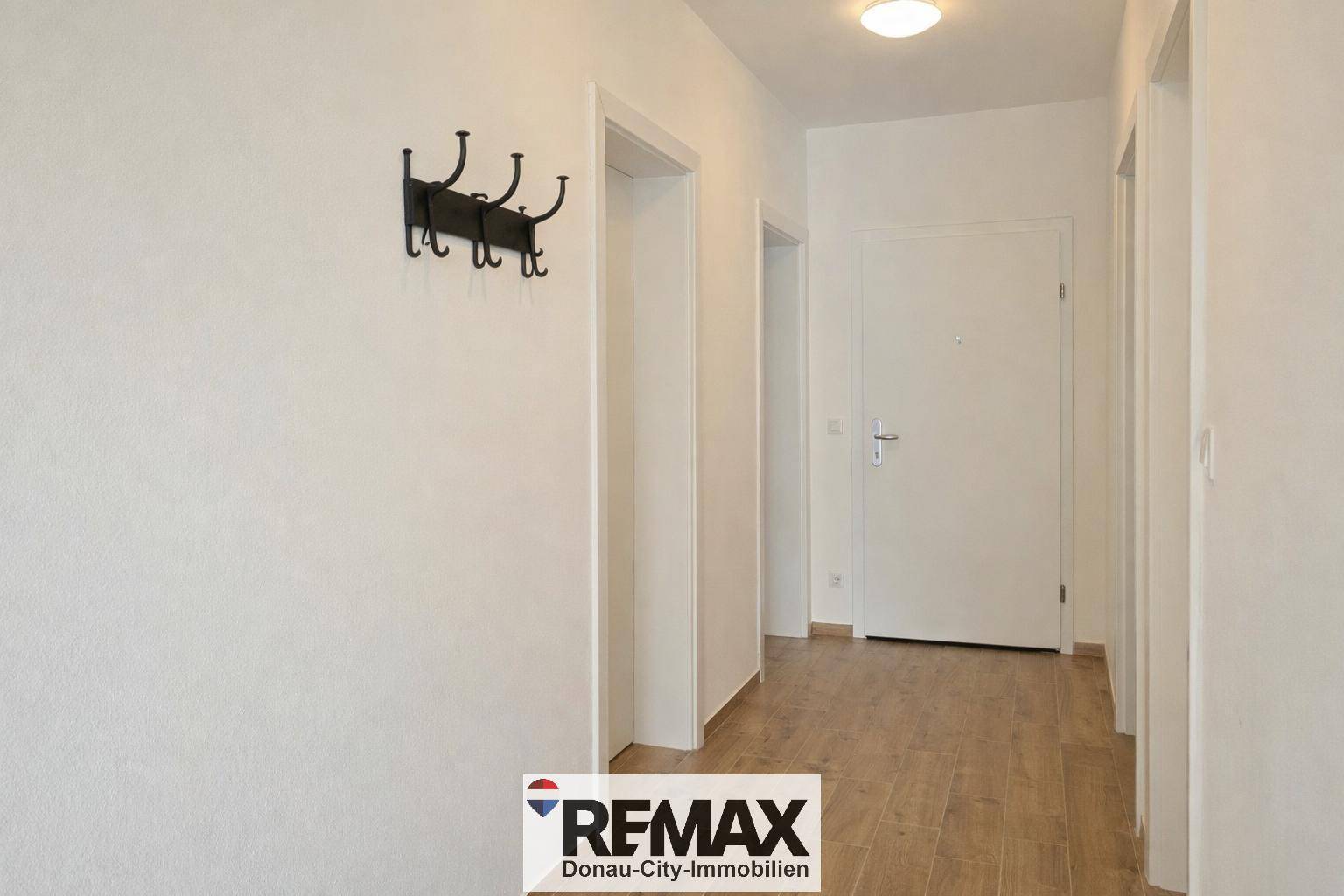 Heller Flur mit Holzboden, weiß gestrichenen Wänden und einem praktischen Garderobenhaken.
