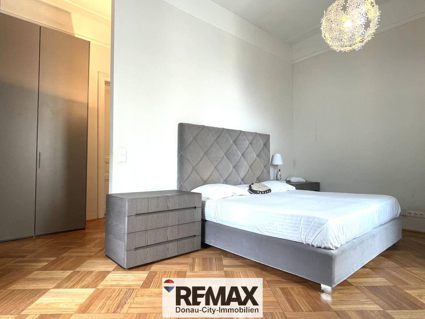 Helles Schlafzimmer mit Parkettboden, großem Bett und integriertem Kleiderschrank.