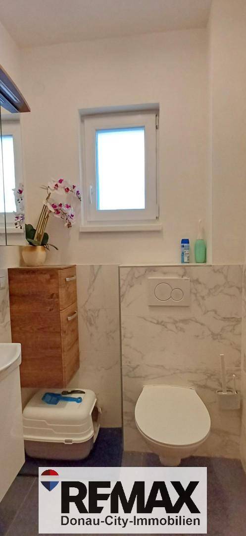 Modernes Gäste-WC mit Fenster, Wand-WC und Marmorfliesen.