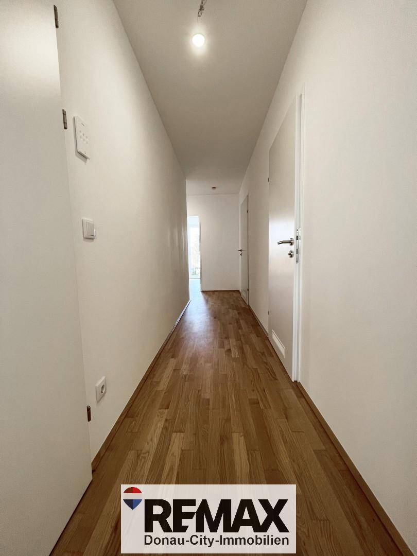 Langer, heller Flur mit Holzboden, der zu den verschiedenen Räumen der Wohnung führt.