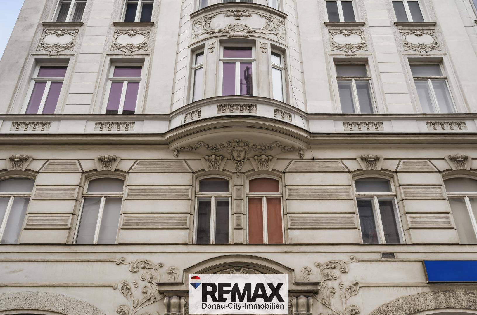 Detailansicht der reich verzierten Fassade eines historischen Gebäudes mit großen Fenstern.