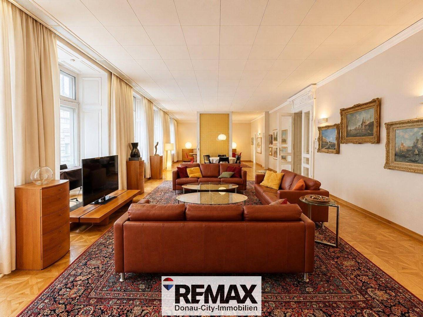 Großzügiges Wohnzimmer mit bequemen Ledersofas, Parkettboden und großen Fenstern.