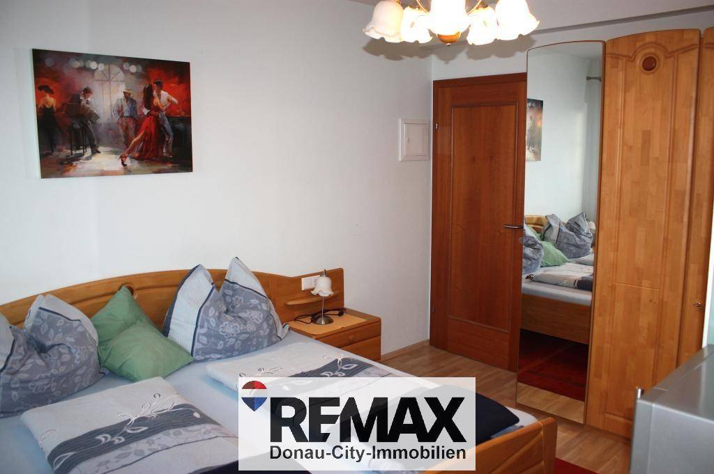 Schlafzimmer mit Doppelbett und einem großen Holzschrank mit Spiegeltür.