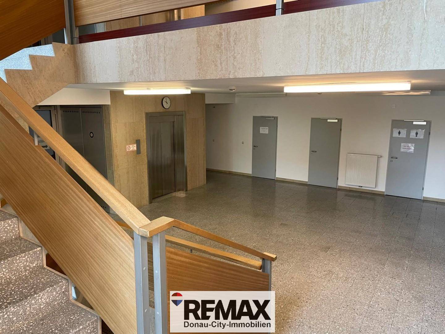 Geräumiger Gemeinschaftsbereich mit Treppe, Aufzug und mehreren Türen zu Büros.