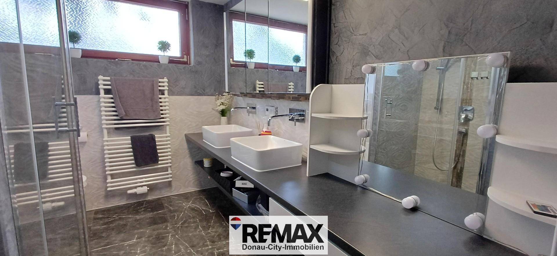 Modernes Badezimmer mit Doppelwaschbecken, großem Spiegel und begehbarer Dusche.