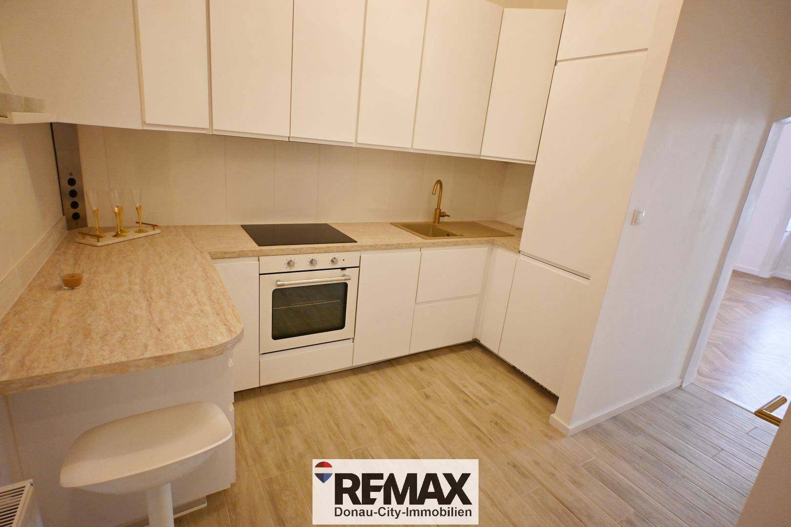 Moderne Einbauküche mit weißen Schränken, Induktionskochfeld und integriertem Backofen.