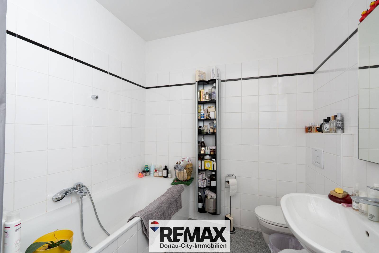 Badezimmer mit weißen Fliesen, einer Badewanne und einem Waschbecken, funktional und hell.