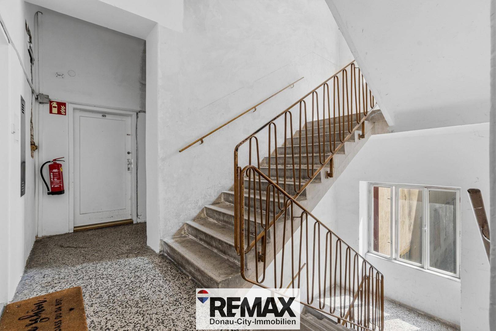 Treppenhaus in einem Altbau mit Terrazzoboden und klassischem Metallgeländer.