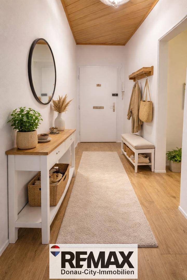 Heller Flur mit Holzboden, Garderobe und einem dekorativen runden Spiegel.