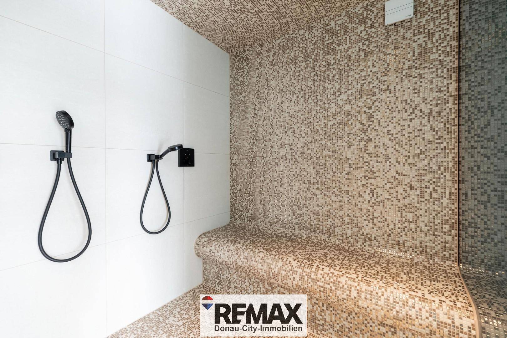 Luxuriöse Dampfdusche mit feinen Mosaikfliesen und modernen schwarzen Armaturen.