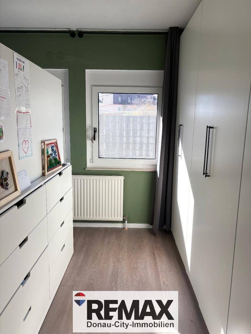 Schlafzimmerbereich mit Einbauschränken, Kommode und Fenster, bietet viel Stauraum.