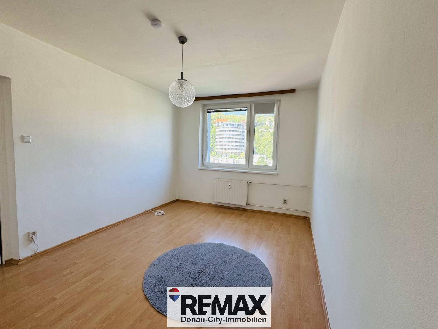 Helles, leeres Zimmer mit Parkettboden und einem Fenster, das viel Tageslicht bietet.