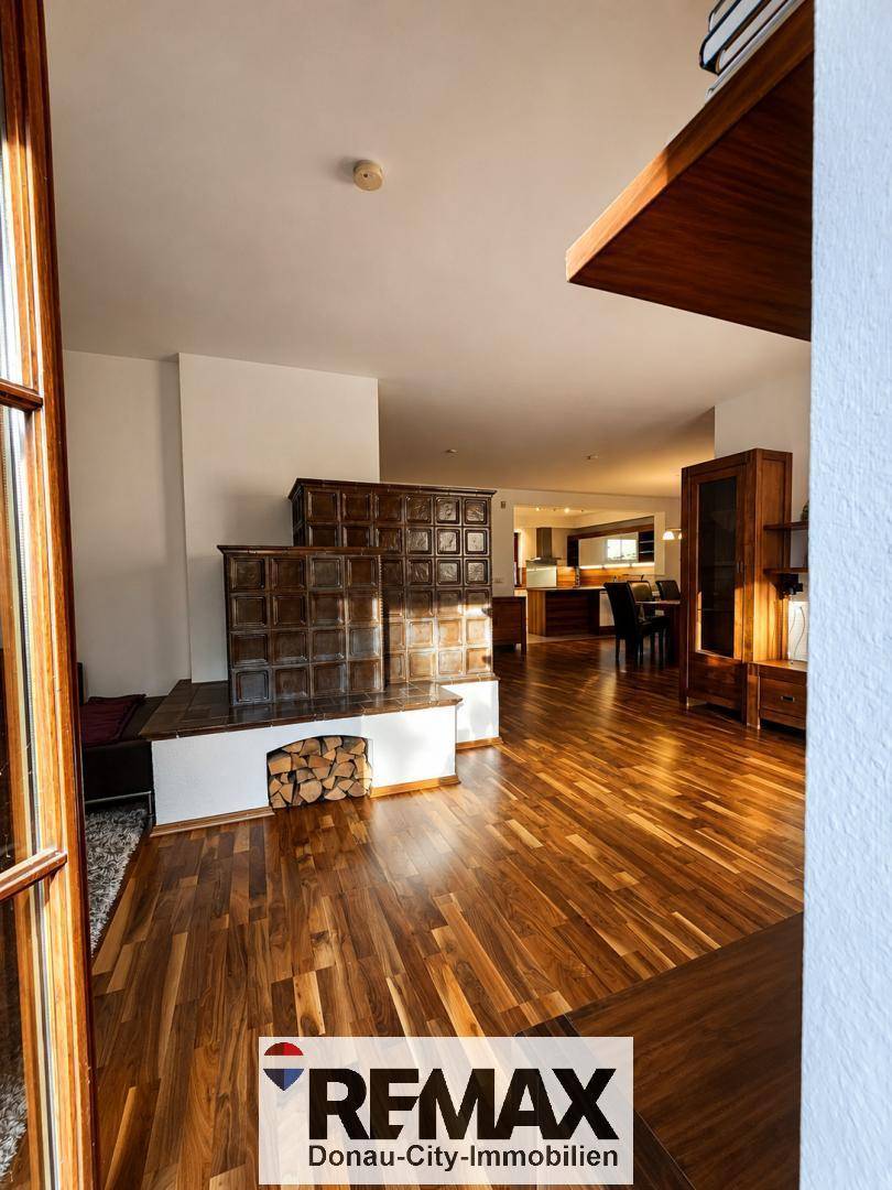 Geräumiges Wohnzimmer mit traditionellem Kachelofen und elegantem Holzboden.