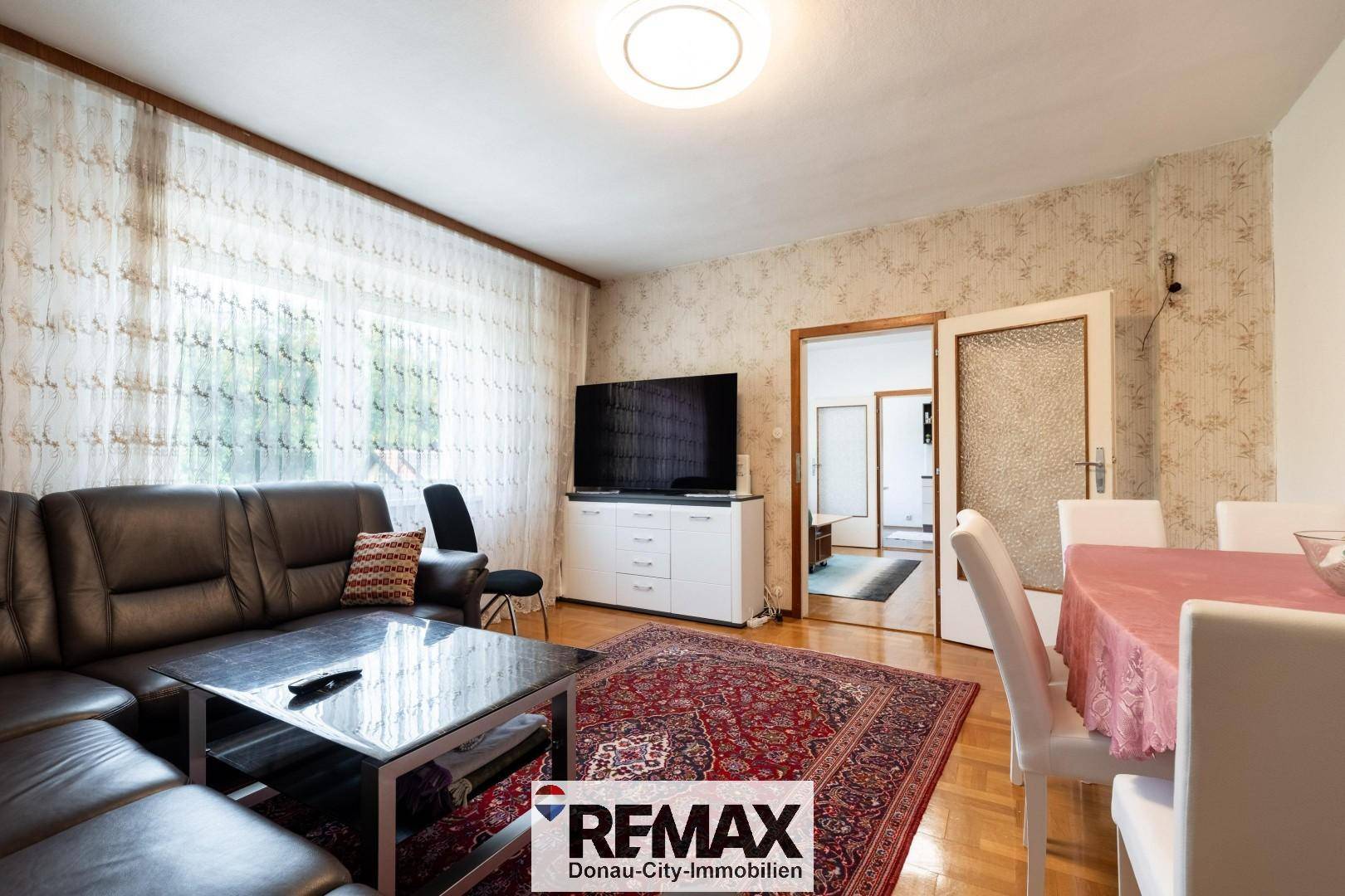 Geräumiger Wohn-Essbereich mit Ledersofa, Fernseher und Esstisch.