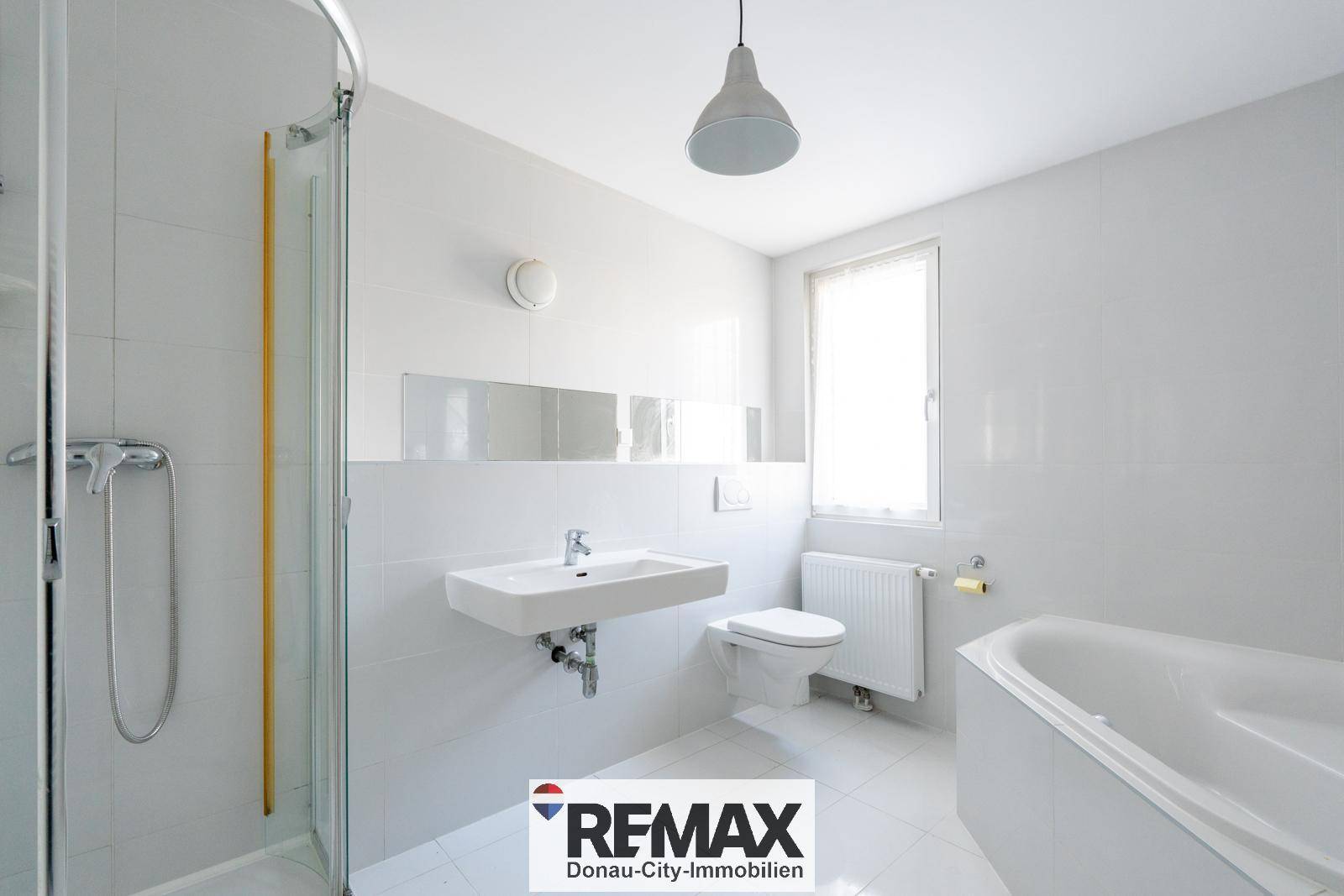Modernes Badezimmer mit weißen Fliesen, Dusche, Eckbadewanne und Fenster.