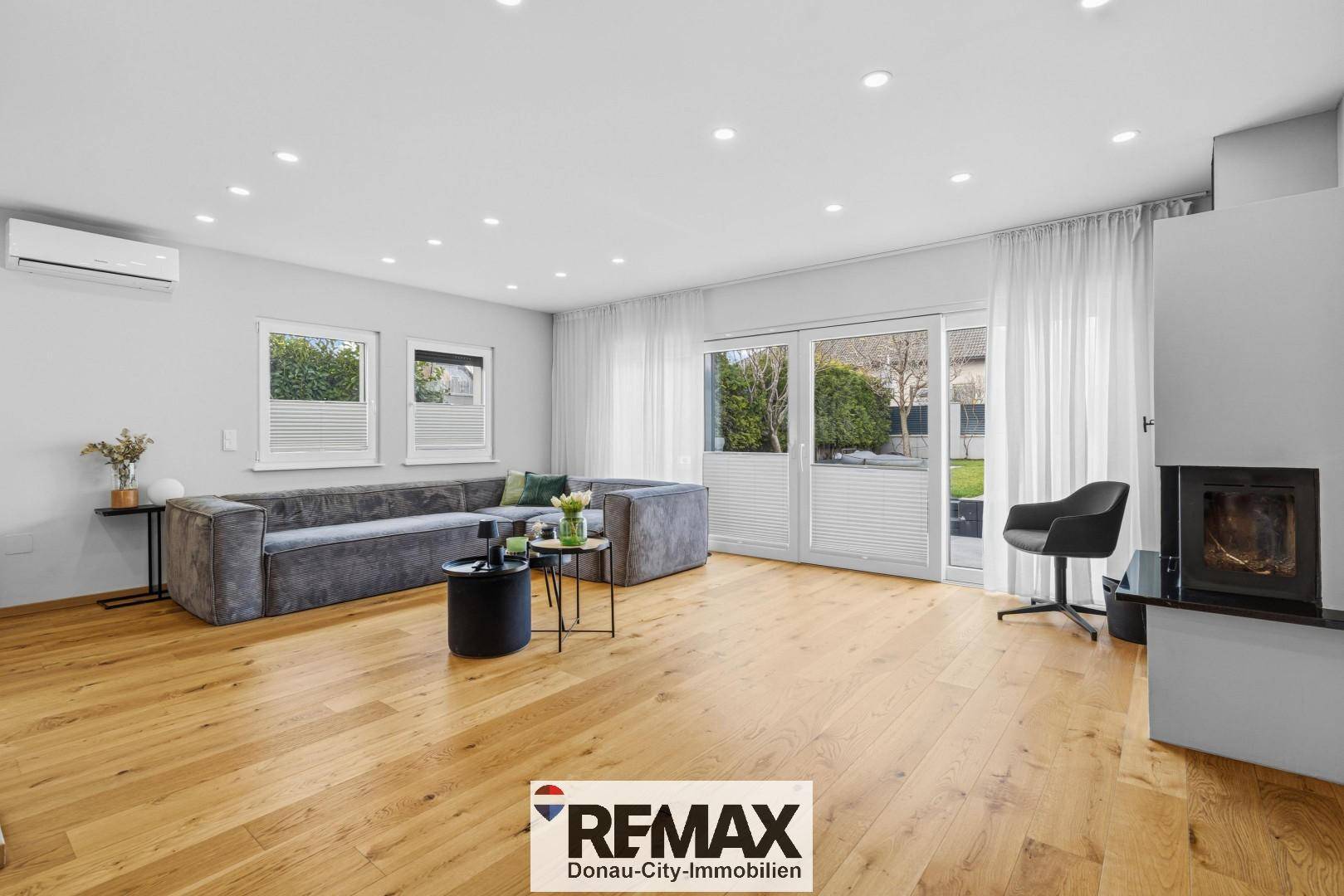 Geräumiges Wohnzimmer mit bequemer Couch, Holzboden und direktem Zugang zum Gartenbereich.