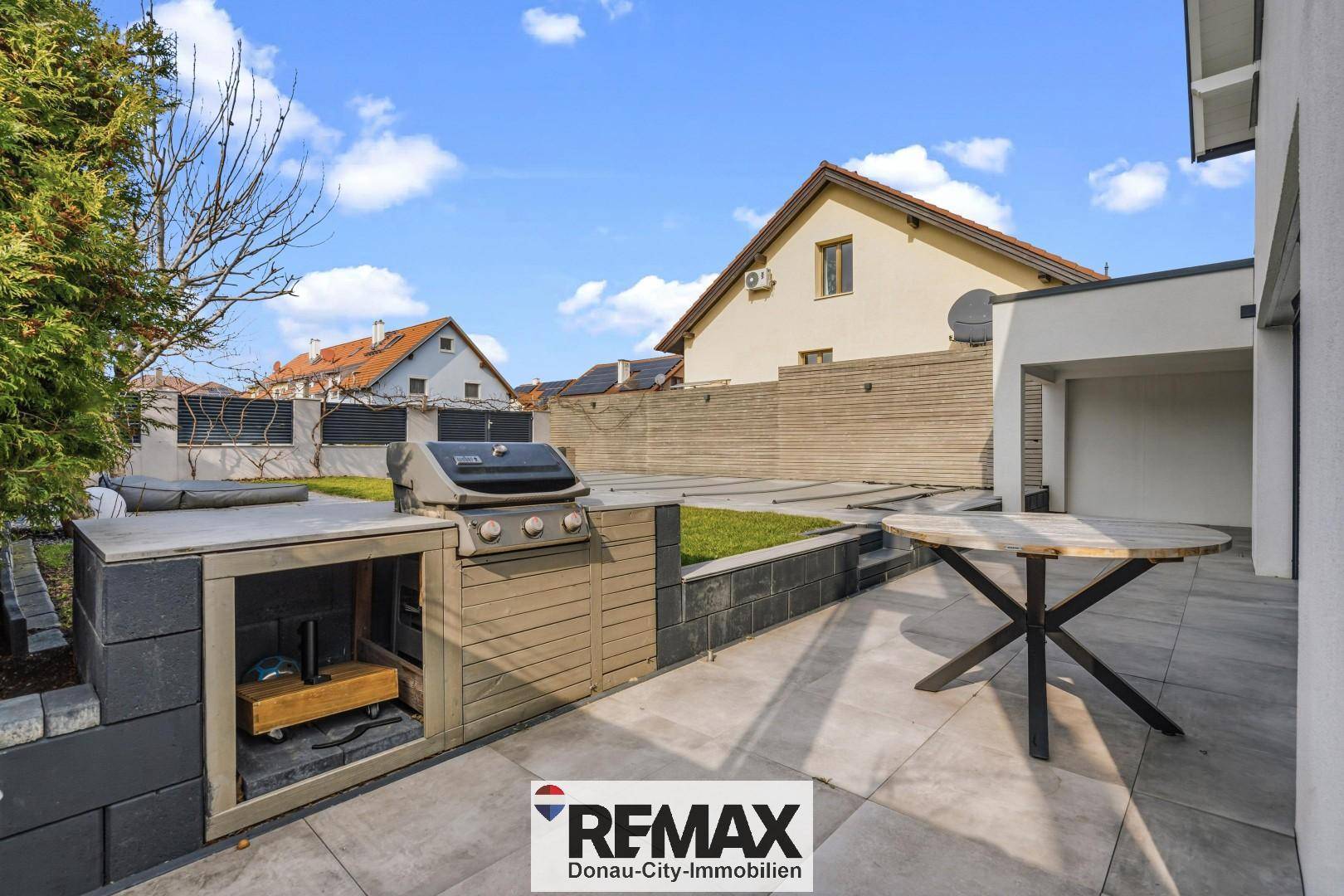 Große gepflasterte Terrasse mit Grillbereich und Esstisch, ideal für Mahlzeiten im Freien.