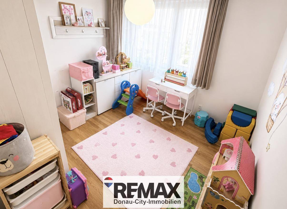 Freundliches Kinderzimmer mit Spielbereich, kleinem Tisch und viel Stauraum.