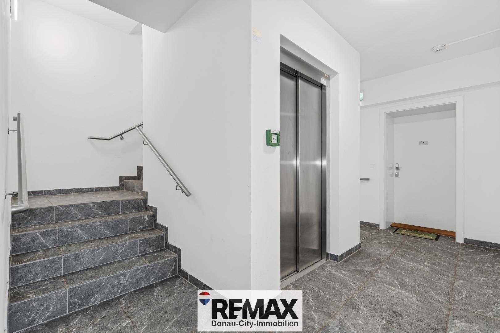 Heller Hausflur mit Treppe und Aufzug im Mehrfamilienhaus.