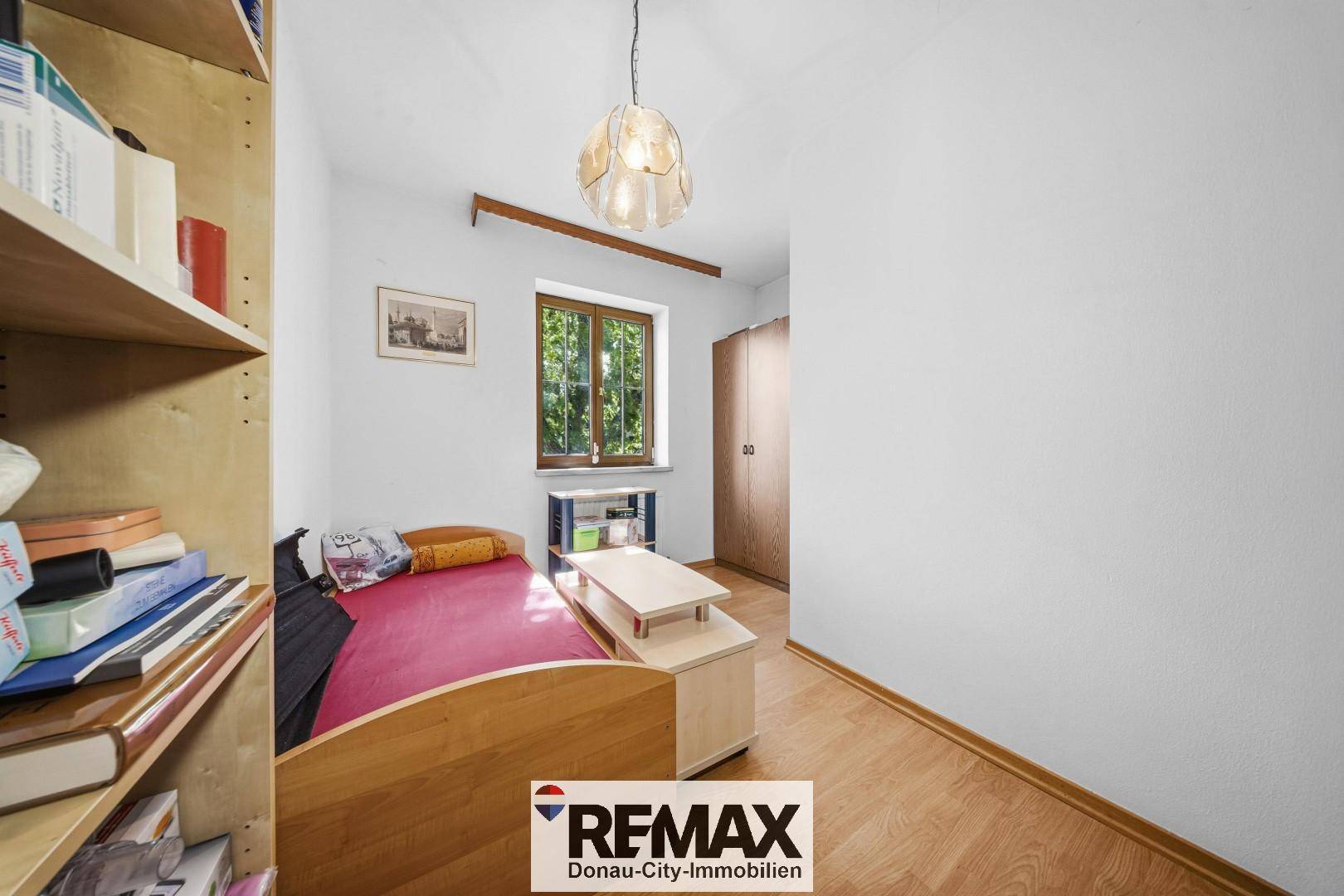 Kleines Schlafzimmer mit Laminatboden, Einzelbett und Regalwand, ideal als Kinder- oder Gästezimmer.