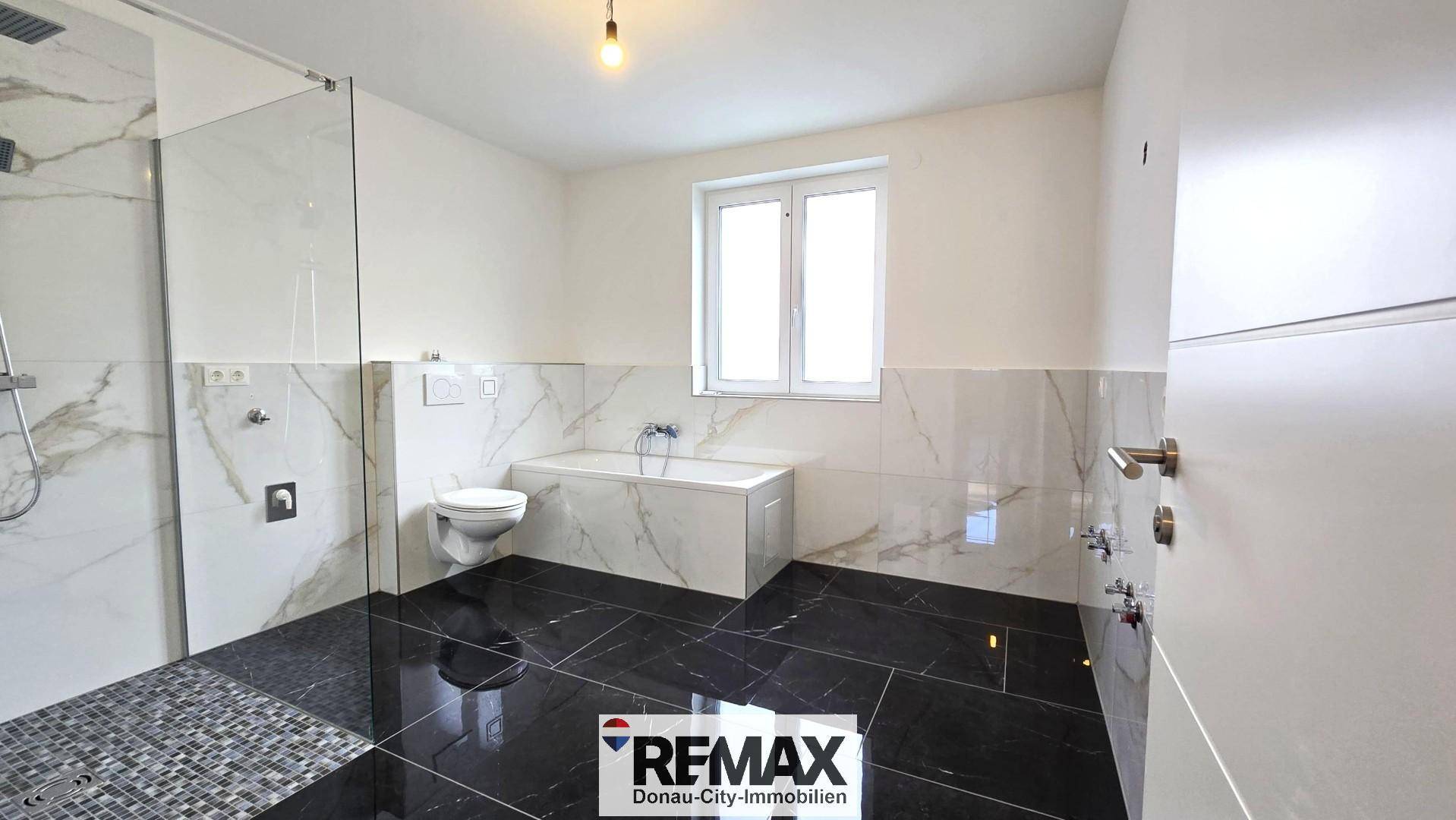 Geräumiges Badezimmer mit Fenster, begehbarer Dusche und moderner Badewanne.
