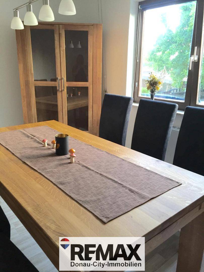 Essbereich mit Holztisch, modernen Stühlen und natürlichem Lichteinfall durch das Fenster.