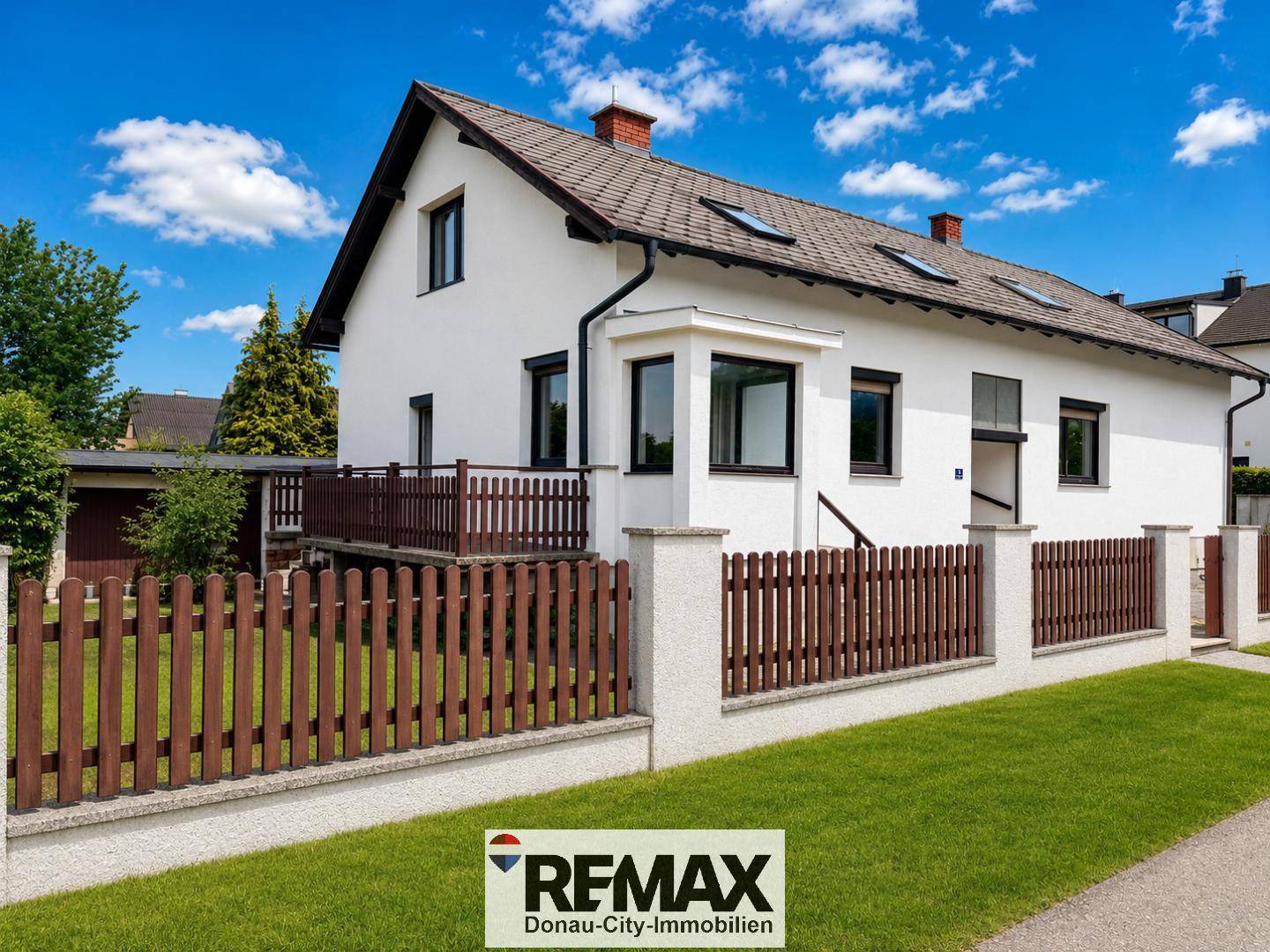 Seitenansicht des Hauses mit gepflegtem Vorgarten und traditionellem Holzzaun.