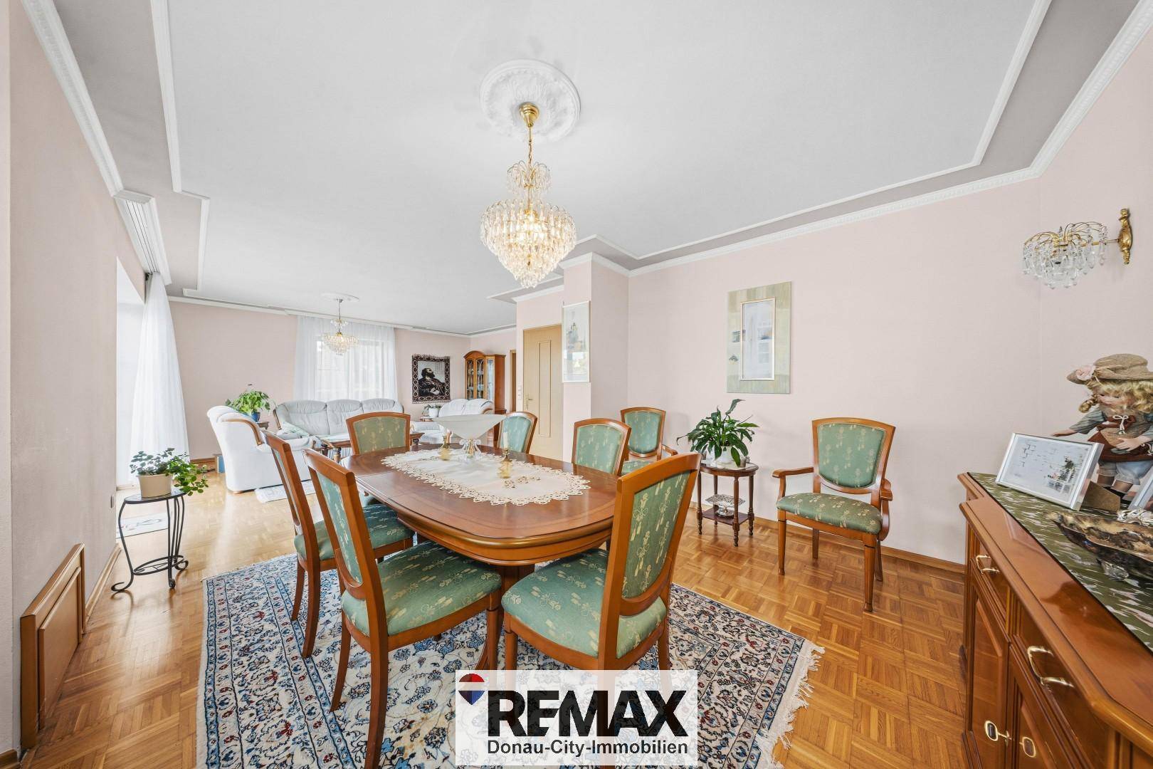 Klassischer Essbereich mit Holztisch, passenden Stühlen und Kronleuchter, angrenzend an das Wohnzimmer.
