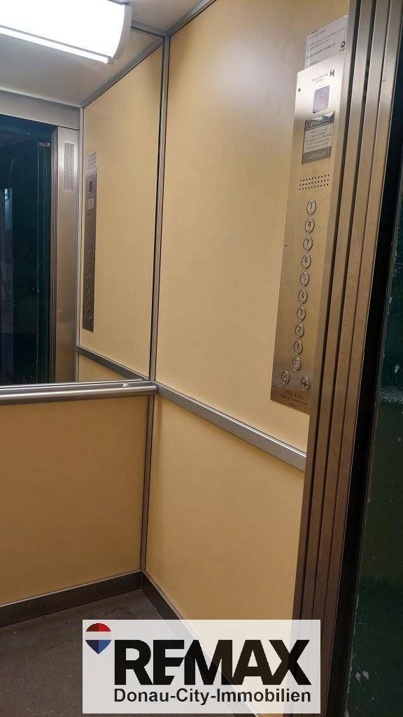 Moderner Aufzug mit beigen Wänden und Edelstahl-Bedienfeld im Gebäude.