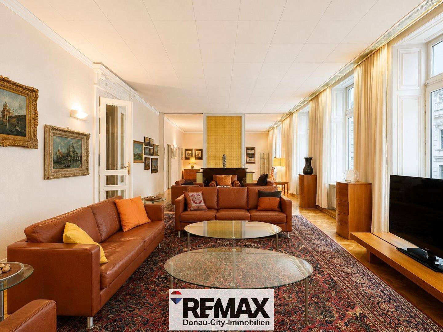 Weitläufiges Wohnzimmer mit mehreren Ledersofas, Parkettboden und viel Tageslicht durch große Fenster.