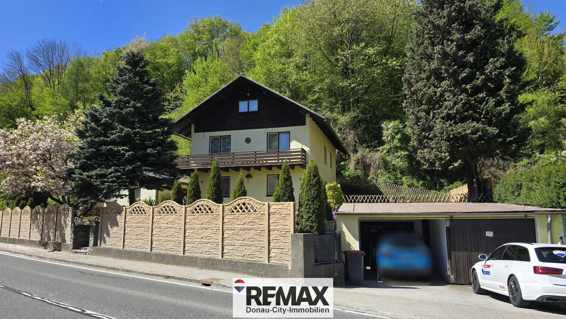Vorderansicht des Hauses mit Garage, Zaun und angrenzender Straße.
