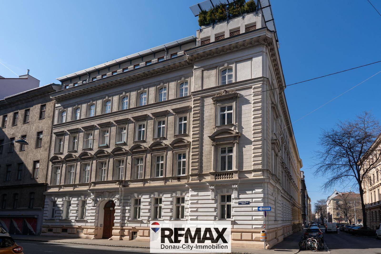 Historisches Gebäude mit klassischer Fassade und Dachterrasse in urbaner Umgebung.