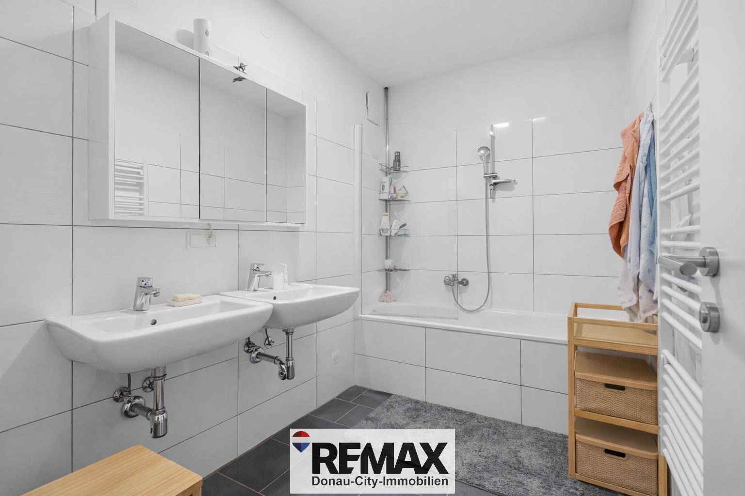 Modernes Badezimmer mit Doppelwaschbecken, Badewanne und weißen Fliesen.