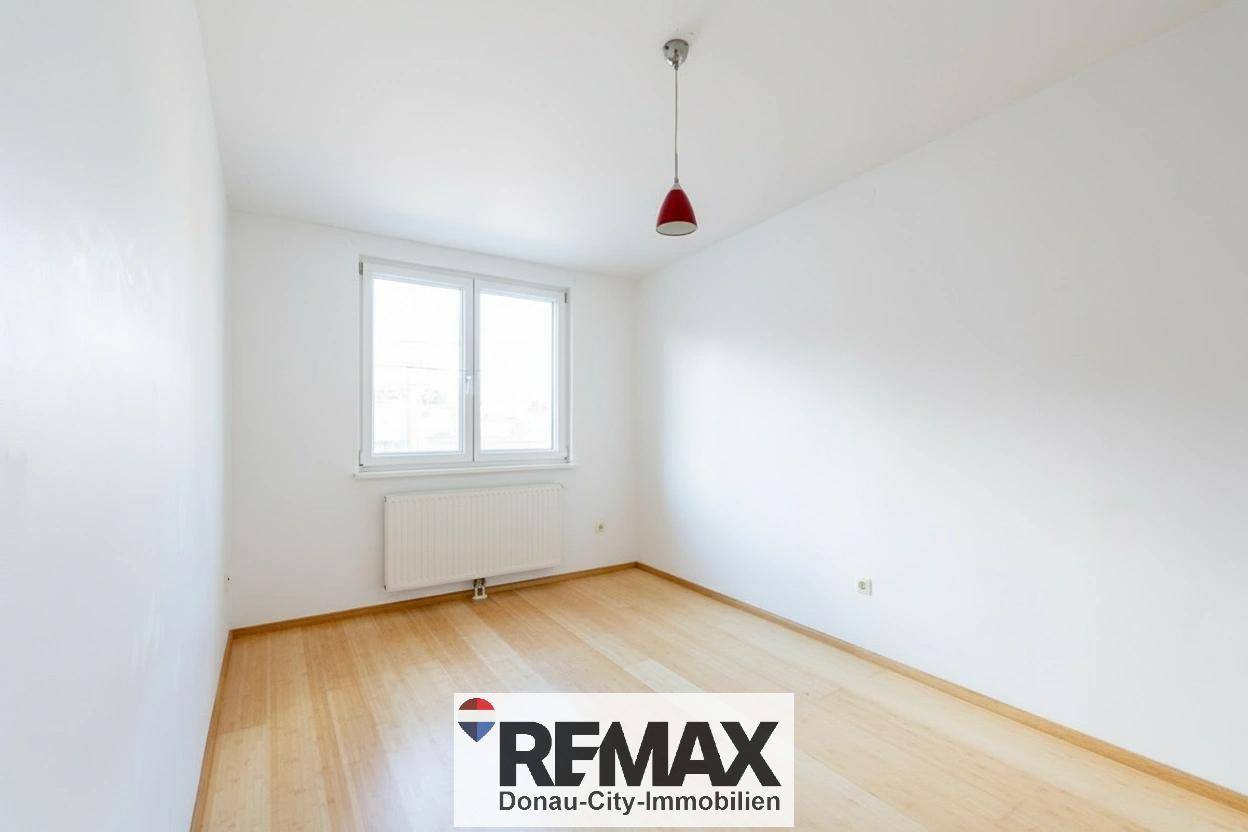 Freundliches Zimmer mit hellem Holzfußboden und Fenster, bereit zur individuellen Gestaltung.