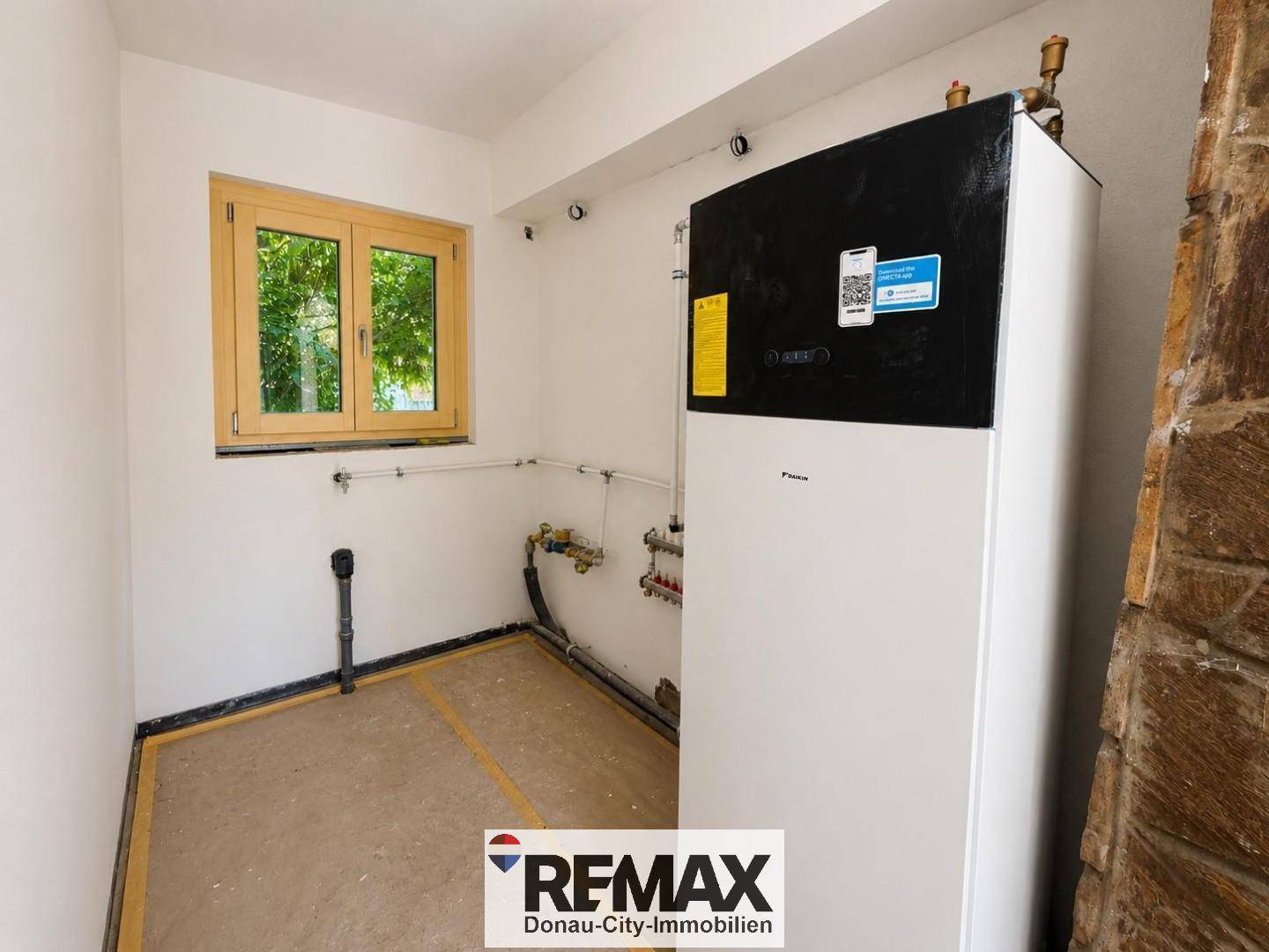 Technikraum mit moderner Wärmepumpe, Fenster und sichtbaren Installationen für das Heizsystem.